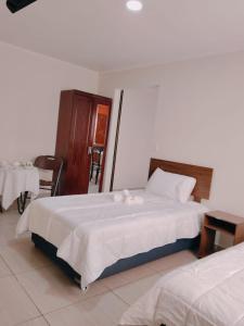 a bedroom with two beds and a table and chairs at Hotel Victoria in Iquique