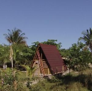 a small house with a red roof in a field at Cabana Villa Caju in Praia dos Algodões