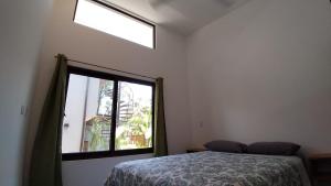 a bedroom with a bed and a large window at Green Turtle Townhome #1 Private Pool & Garden 300 Mtrs to Beach in Tamarindo
