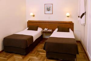 a hotel room with two beds and a table at Hotel Muñiz in Bahía Blanca