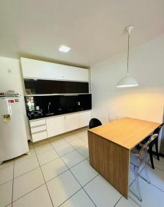 a kitchen with a wooden table and a refrigerator at ILOA Apto térreo 03k in Barra de São Miguel