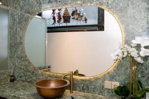 a bathroom with a large round mirror over a sink at Villa Tria Laweyan Solo in Purwosari