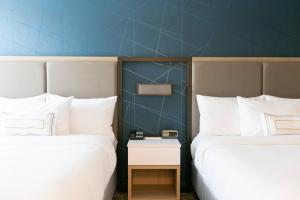 two beds in a hotel room with a table between them at SpringHill Suites by Marriott South Bend Notre Dame Area in South Bend