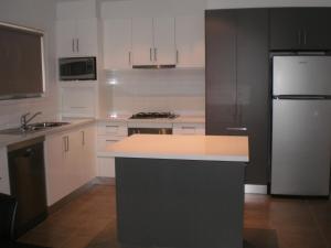 cocina con armarios blancos y nevera blanca en King Street Apartments, en Warrnambool