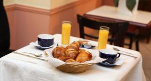 una mesa con una cesta de cruasanes y zumo de naranja en Hotel Celtic en París