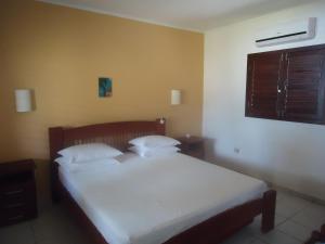 a bedroom with a bed with white sheets and a window at Ekoara Bangalos in Jacumã
