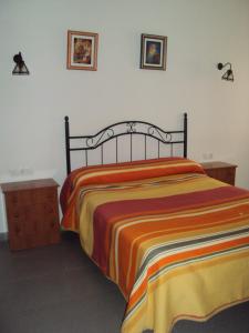 1 dormitorio con 1 cama con una manta a rayas de colores en El Aceitón, en Cortegana