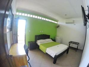 a bedroom with a bed with a green wall at Monteverde Hotel in La Dorada