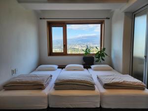 three beds in a room with a window at Palm Tree Villa in Seogwipo