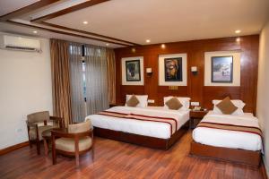 una camera d'albergo con due letti, un tavolo e delle sedie di Aryatara Kathmandu Hotel a Kathmandu