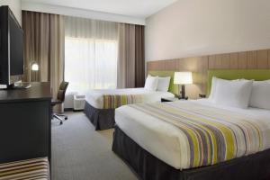 um quarto de hotel com duas camas e uma secretária em Country Inn & Suites by Radisson, Brunswick I-95, GA em Brunswick