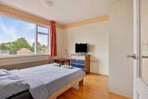 a bedroom with a bed and a tv and a window at Eindhoven City Center Apartment in Eindhoven
