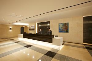 two men standing at a reception desk in a lobby at Hotel Prumir in Hwaseong