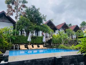 a resort pool with lounge chairs and umbrellas at Sela Cottages in Toyapakeh