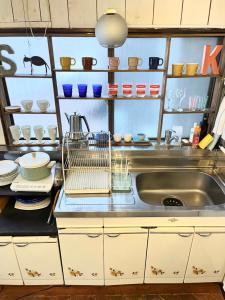 a kitchen with a sink and shelves with dishes at Ohmachi Junxion in Kamakura +32 photos
