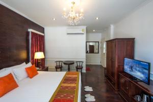 a bedroom with a large bed and a chandelier at Le Bouton D'or Boutique Hotel in Thakhek