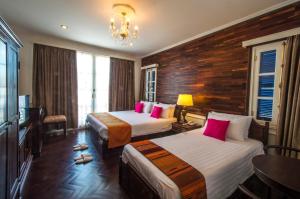 a hotel room with two beds and a chandelier at Le Bouton D'or Boutique Hotel in Thakhek