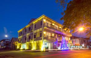 a white building with lights on a street at night at Le Bouton D'or Boutique Hotel in Thakhek +25 photos