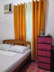 a bedroom with a bed and curtains and a dresser at RM Homestay in Siquijor