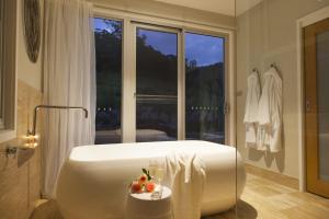 a bathroom with a large white tub in front of a window at Wilderberry Cottage in Berry
