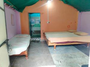 a room with two beds and a mirror at GOLDENGARDEN COTTAGES in Hampi