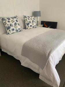 a bedroom with a white bed with blue and white pillows at Silver Linings Cottage in Parys