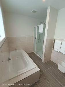a white bathroom with a tub and a shower at Waterview Spacious Bliss - 2 Beds in Porirua