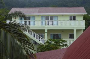 a white building with a balcony and trees at Chez Payet Airport Guesthouse in Pointe Larue