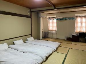 two twin beds in a room with two windows at Aigakusou in Nozawa Onsen