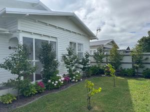 a white house with a garden in front of it at Luxury Magnolia Bungalow in Hastings