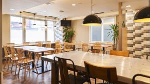 a restaurant with tables and chairs and windows at Hotel Paco Obihiro Ekimae in Obihiro