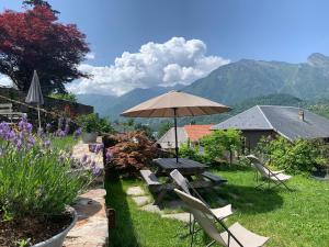 a picnic table and chairs with an umbrella in a garden at Au Cheval Blanc - appartements et chambres d'hôtes in Albertville