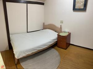 een kleine slaapkamer met een bed en een nachtkastje bij Tokyo Kakan in Tokyo