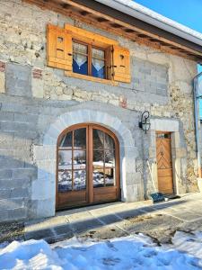 a stone building with a wooden door and windows at Maison au cœur du Jura in Saint-Laurent-en-Grandvaux