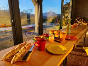 a wooden table with food and drinks on a table with a window at Les couleurs du Cagire in Estadens