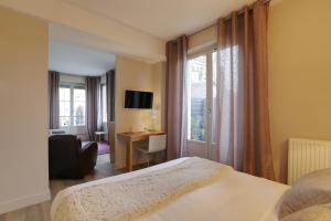 a bedroom with a bed and a desk and a window at Hôtel Cardinal in Rouen