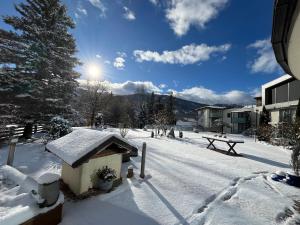 a snow covered yard with a picnic table and a tree at Hartweger's Hotel in Haus im Ennstal