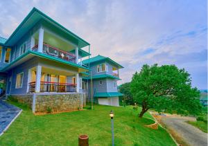 a blue and white house with a grass yard at Priyas Villa Vagamon by VOYE HOMES-Scenic Mountain View in Vagamon