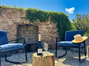 a bottle of wine sitting on a table with two chairs at Rhun Even, charmante maison bretonne pour 6 personnes in Plougasnou