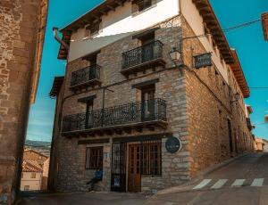 a tall brick building with balconies on a street at El Refugio Valdelinares Gastro Hostal in Valdelinares