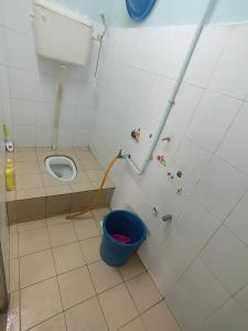 a bathroom with a toilet and a blue bucket at Dinaz Homestay Taman Limbungan Permai Melaka in Melaka