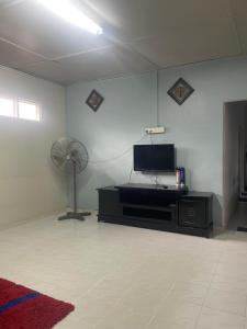 un soggiorno con TV a schermo piatto e ventilatore di Hj Hassan Guest House Bungalow A a Kuala Terengganu