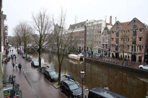 una calle de la ciudad con coches estacionados junto a un río en redlight canalview city centre, en Ámsterdam