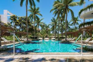 una piscina en el complejo con palmeras en el fondo en Donoma Las Terrenas Beach Hotel & Spa, Autograph Collection, en Las Terrenas