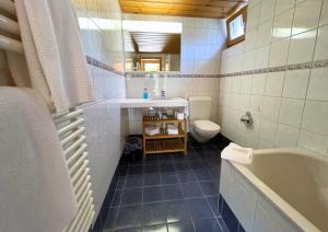 a bathroom with a tub and a sink and a toilet at Eiger Lodge Easy in Grindelwald +29 photos