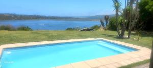a large blue swimming pool next to a lake at Island Lake Villa and Bungalow in Wilderness +28 photos