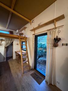 a room with a window and a ladder and a table at Tiny house au coeur de la foret in Les Martys +3 photos