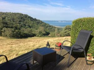 a deck with a chair and a table and a view of the ocean at Rhiwiau Guesthouse in Llanfairfechan