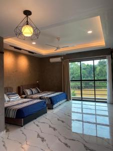 two beds in a room with a large window at Lipis Riverfront Resort in Kuala Lipis