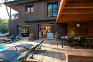 een huis met een terras met een tafel en stoelen bij La Villa Nature Canopée du Lac in Seignosse